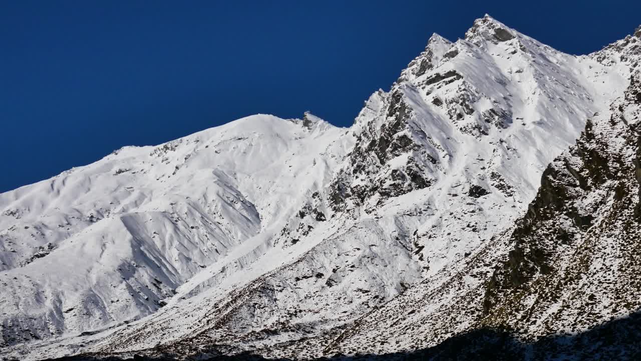 Panning shot of beautiful snowy mountains lighting by sun against blue sky - Rees Valley,Fiordland National Park