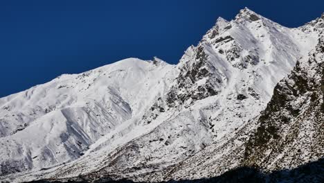 panning shot of beautiful snowy mountains lighting by sun against blue sky - rees valley,fiordland national park