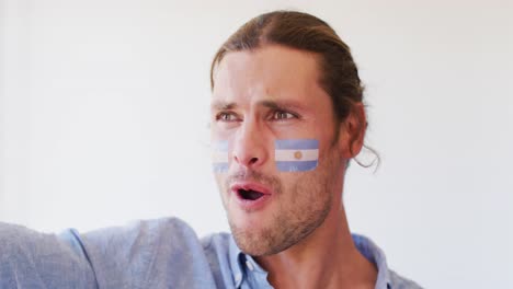 image of happy caucasian man with flag of argentina cheering