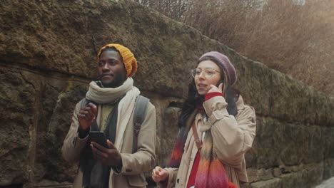 pareja de turistas diversos caminando por la ciudad vieja y usando un teléfono inteligente