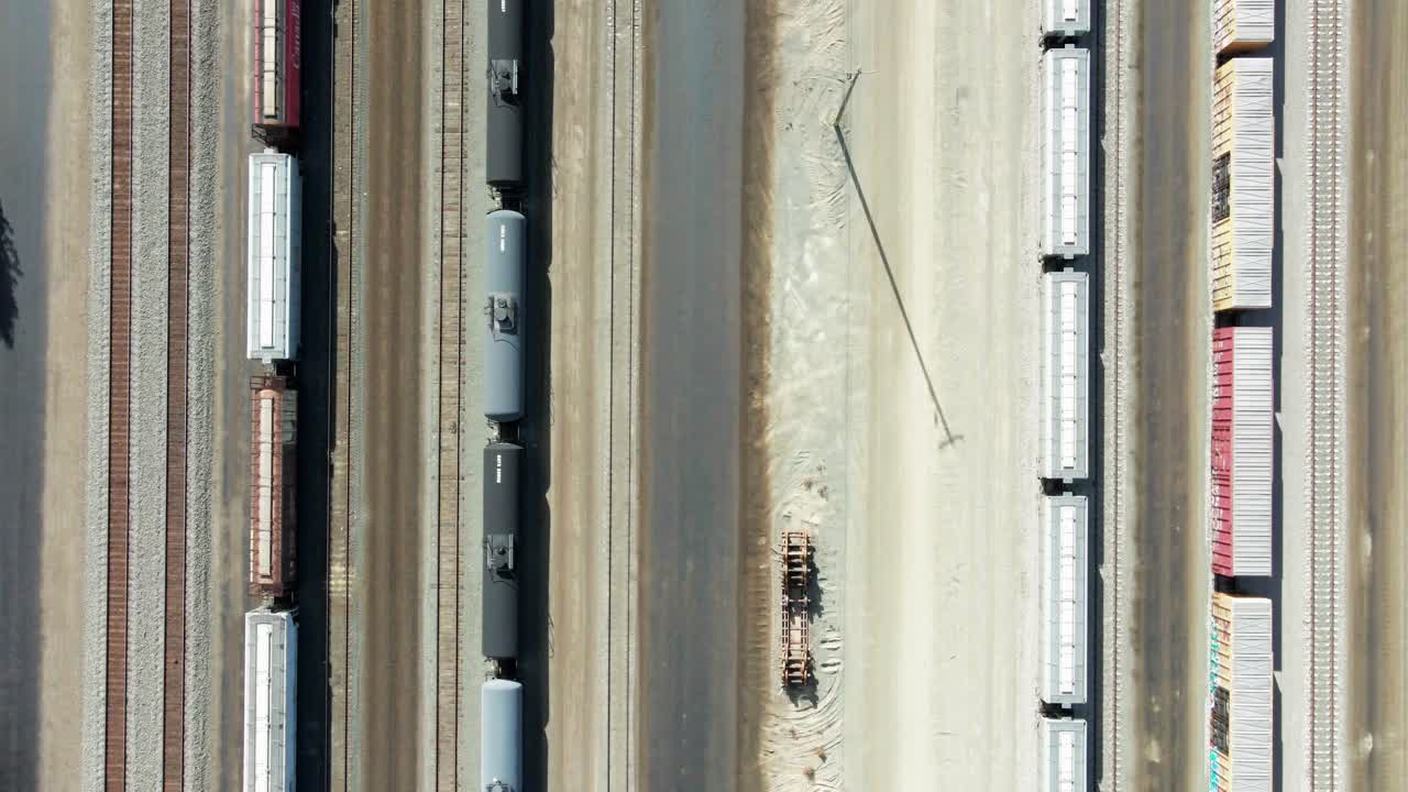 camión con vista de pájaro disparado por un dron que volaba sobre la estación de ferrocarril en un entorno desértico en un día soleado con carga y tanques y líneas eléctricas