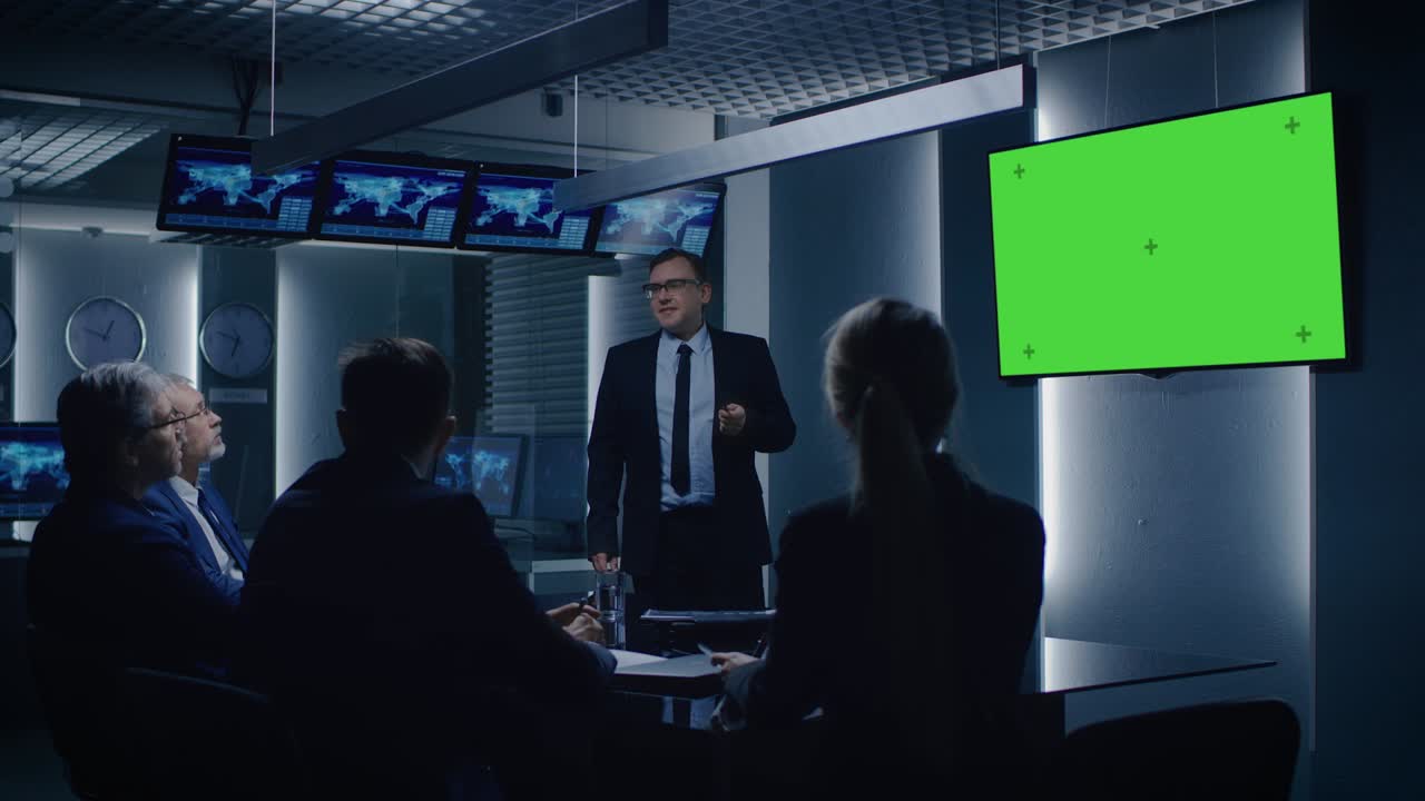 Chief Strategy Officer Showing Report to a Board of Directors and Business Partners, Using Green Mock-up Screen in the Monitoring Room.
