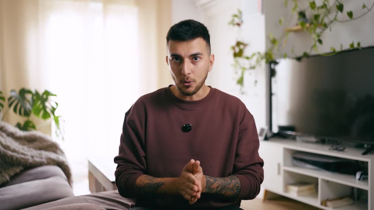 Young Man Talking and Gesturing to Camera in Living Room