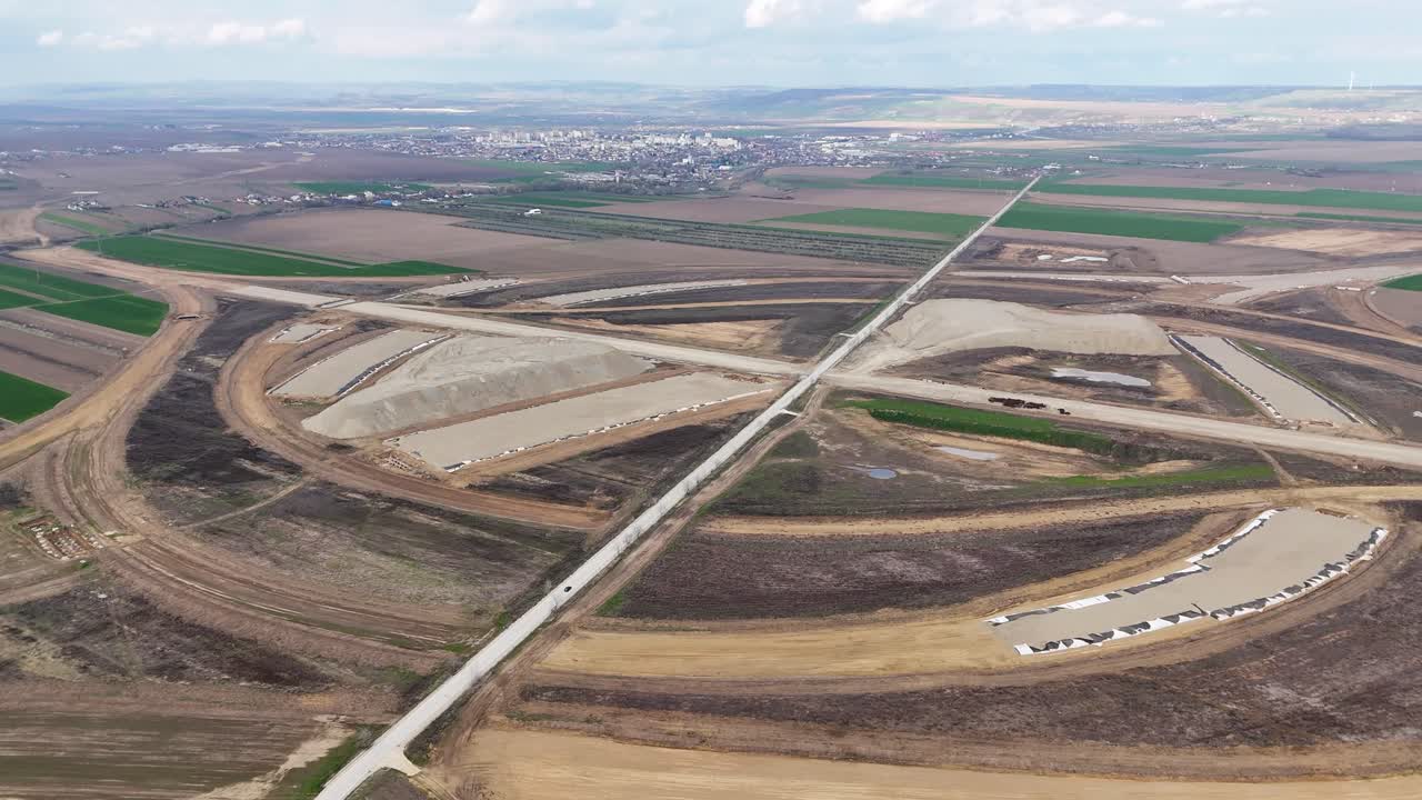 Dronekuva suuresta, rakenteilla olevasta moottoritien liittymästä lähellä Pașcania, Romania, kaupungin näkyessä taustalla