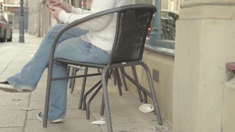 mujer que usa un teléfono móvil fuera de un café callejero urbano