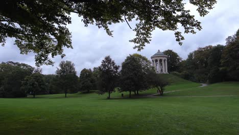 una familia está caminando por el jardín inglés de munich, subiendo las escaleras hasta el famoso templo de monopteros