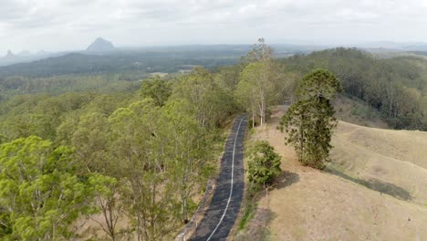 carretera asfaltada en el parque nacional glass house mountains con vistas a las colinas en forma de cúpula en queensland, australia