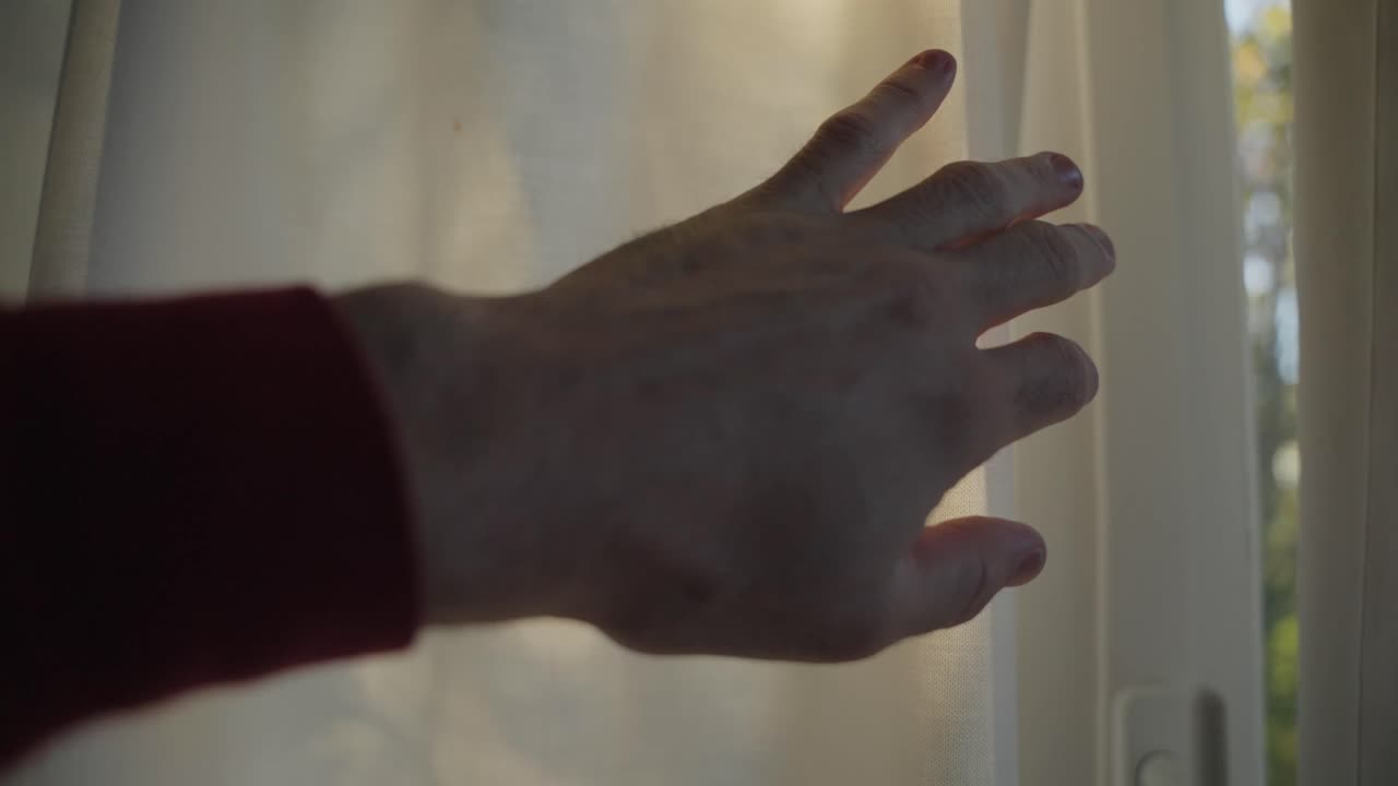 Man pulls open window curtain or drape to reveal sunny day outdoors as sun flares camera in bright beam of warm light. Symbol of faith hope and positive energy. New green solutions for better future