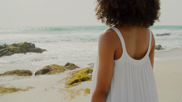 Vista posteriore di donna afroamericana in piedi in spiaggia 4k