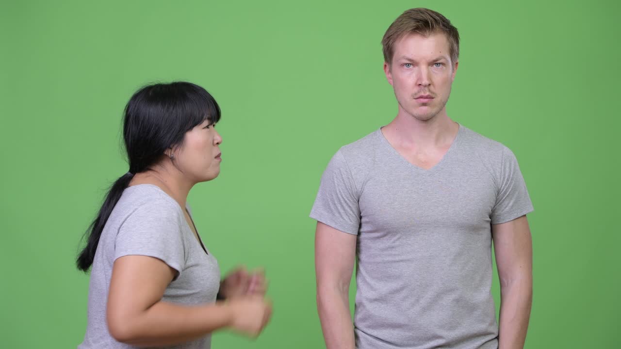 Angry overweight Asian woman talking to calm young man