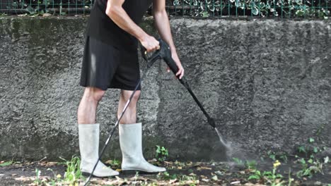 a man who cleans concrete wall using a high pressure washer