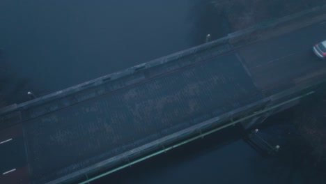 Top-shot-of-car-crossing-bridge-with-blanket-of-fog-during-early-moody-morning-hours