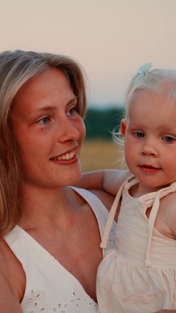 Mutter hält ihre kleine Tochter auf einem Feld bei Sonnenuntergang