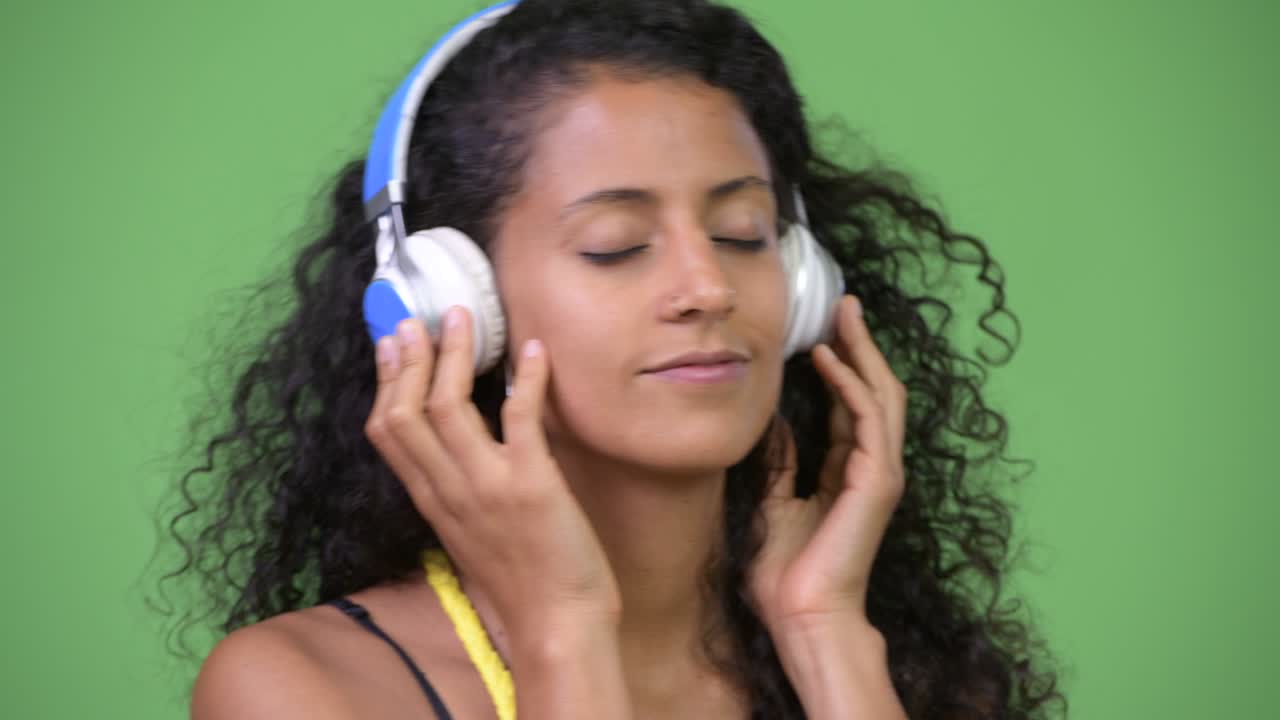 Young beautiful Hispanic woman listening to music