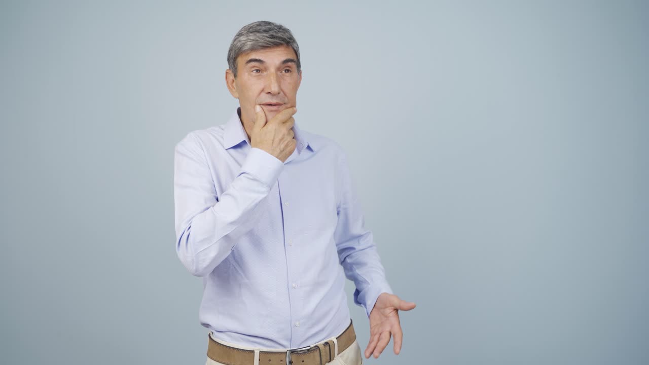 un anciano pensativo hacia la cámara.