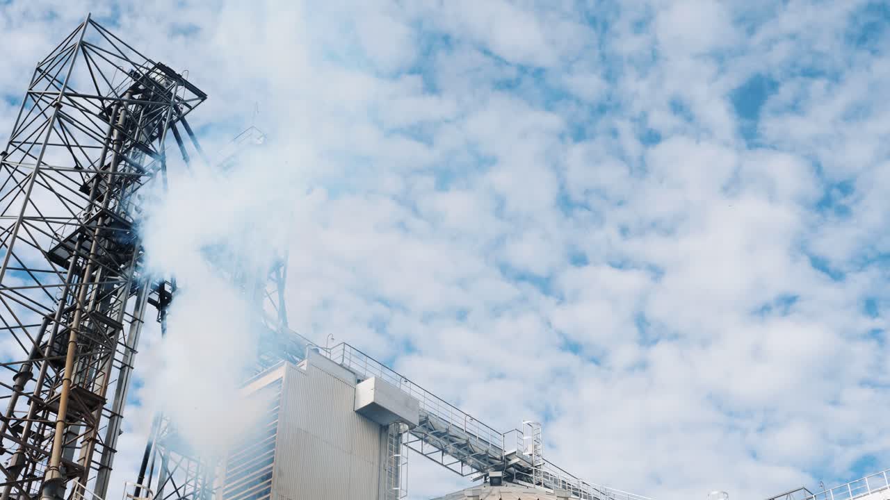 Thick smoke from grain dryer outdoors. White vapor goes into the atmosphere from modern industrial farm. Harmful factory against the sky. Air pollution