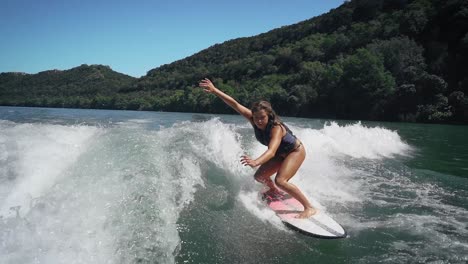 female wakesurfer landing big air three sixty while wakesurfing off the back of a speed boat on lake austin, texas