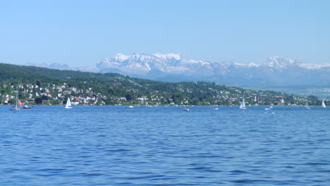 sailboats on lake zurich with the swiss alps mountains in background