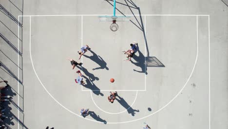 top down drone shot of men playing basketball on outdoor court, shadows and people