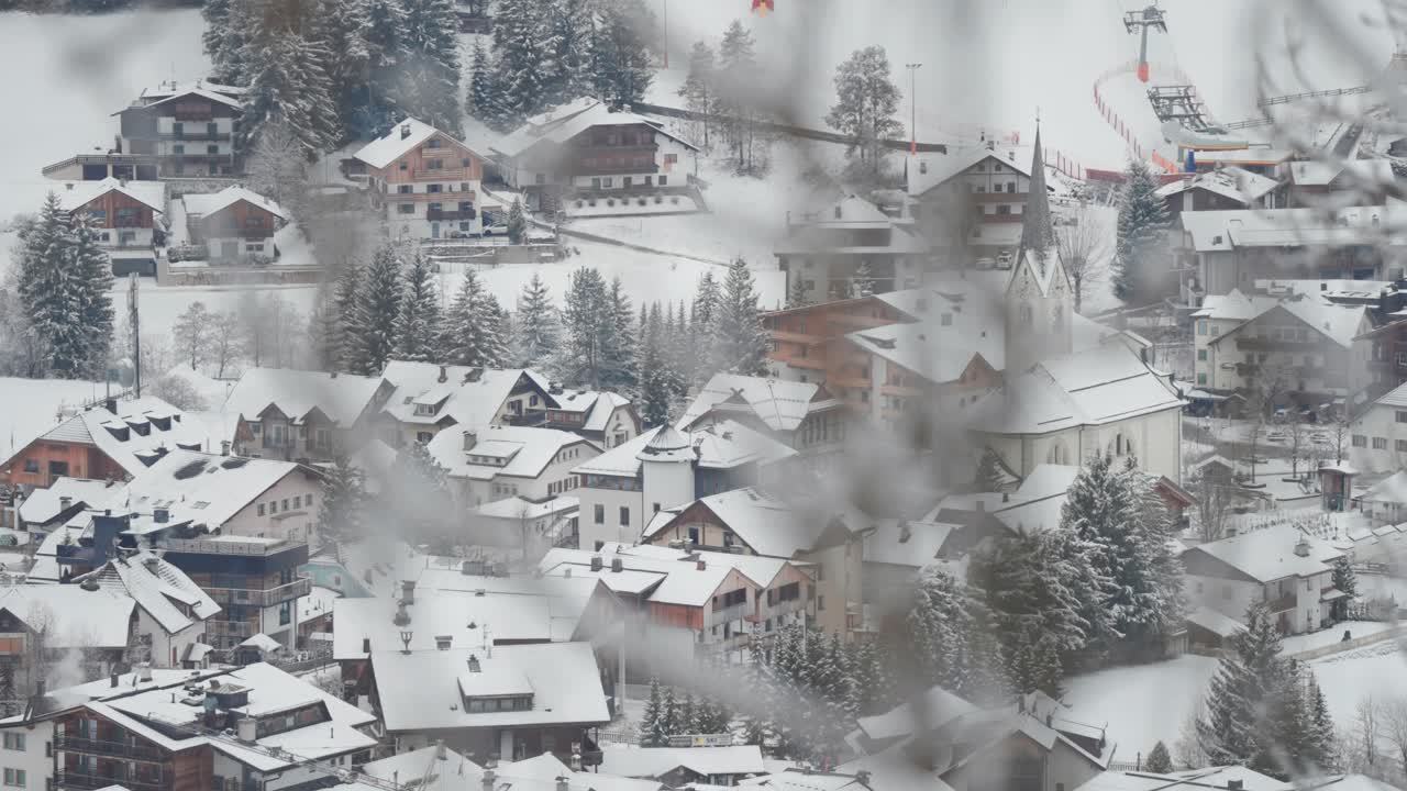 A quiet winter morning in a Dolomitic town, with snowy streets and pine trees in the background.