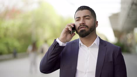 Seriöser-Geschäftsmann,-Der-Auf-Der-Straße-Per-Smartphone-Spricht