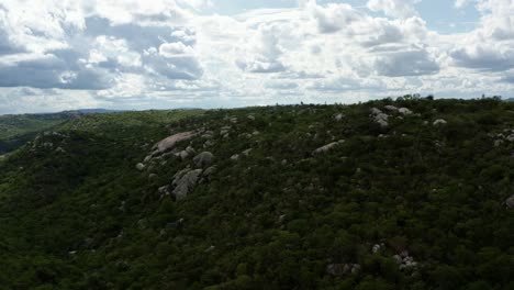 Trucking-right-aerial-drone-shot-of-the-beautiful-green-and-rocky-countryside-of-Sítio-Novo,-Brazil-in-the-state-of-Rio-Grande-do-Norte-with-rocky-cliffs-and-wild-brush-surrounding-farmland