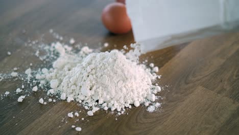 person sprinkling flour on table next to eggs to prepare a dough