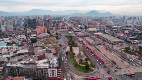 Vista-De-Pájaro-De-La-Plaza-Arturo-Prat-Con-Una-Línea-De-Nuevos-Autobuses-Rojos-Al-Costado,-El-Transporte-Público-De-Vanguardia-De-Santiago-De-Chile