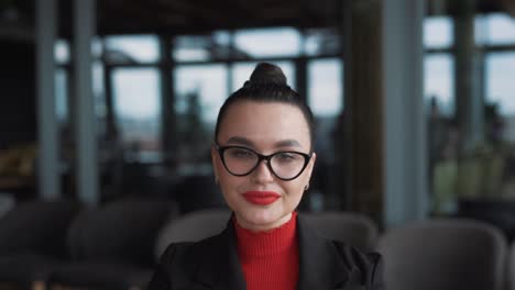 retrato de una hermosa mujer joven con gafas y aparatos ortopédicos, una freelancer, se sienta en un elegante restaurante vestida con ropa de negocios, usando gafas y sonriendo