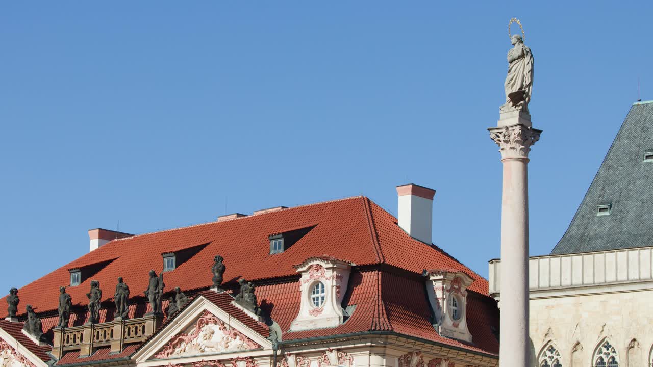 Baroque rooftop with statues, column monument, and clear blue sky in Prague, Czech Republic