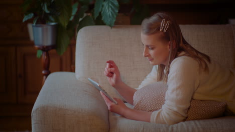 Young-Woman-Laying-On-Softa-While-Doing-Online-Shopping-On-Digital-Tablet-Computer-At-Home-1