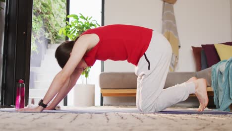 mujer transgénero caucásica no binaria que practica yoga, estiramiento
