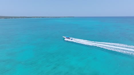 Un-Pequeño-Barco-Recorre-Aguas-Cristalinas-Y-Azules-Hasta-Una-Isla-Exótica,-órbita-Aérea.