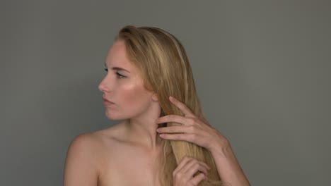 the woman is combing her healthy long blond hair with her hands