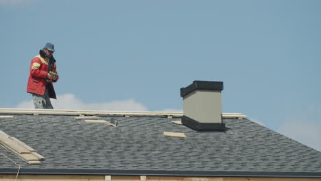 the builder is working on the roof of the house - laying shingles