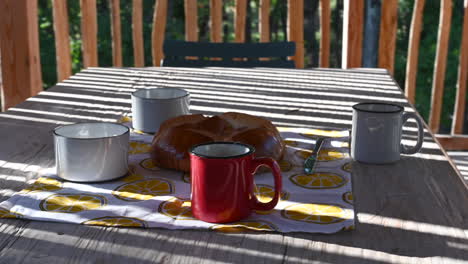 cups of hot tea with evaporating water and a bun, wooden table, panning shot