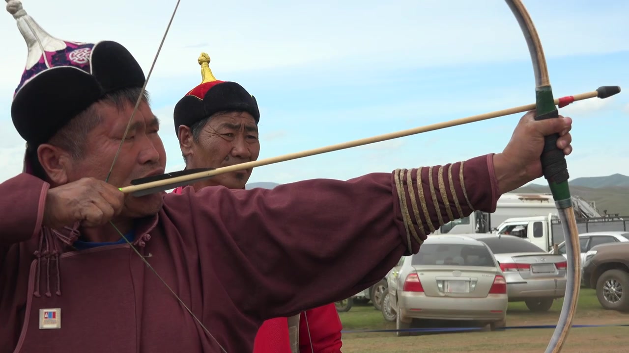 Mongolisk bågskytt siktar med traditionell båge vid utomhustävling