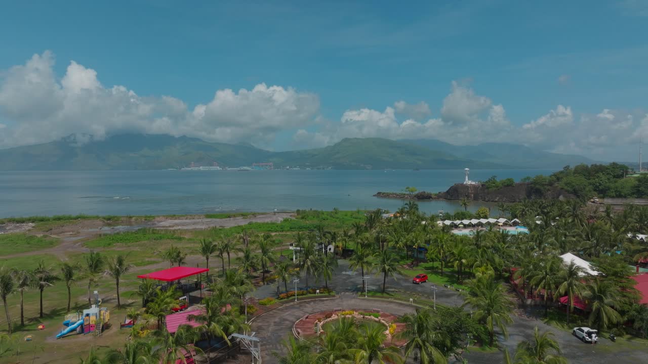 A cinematic dolly-out drone shot reveals a stunning section of the resort, featuring lush palm trees and a distant shimmering pool.