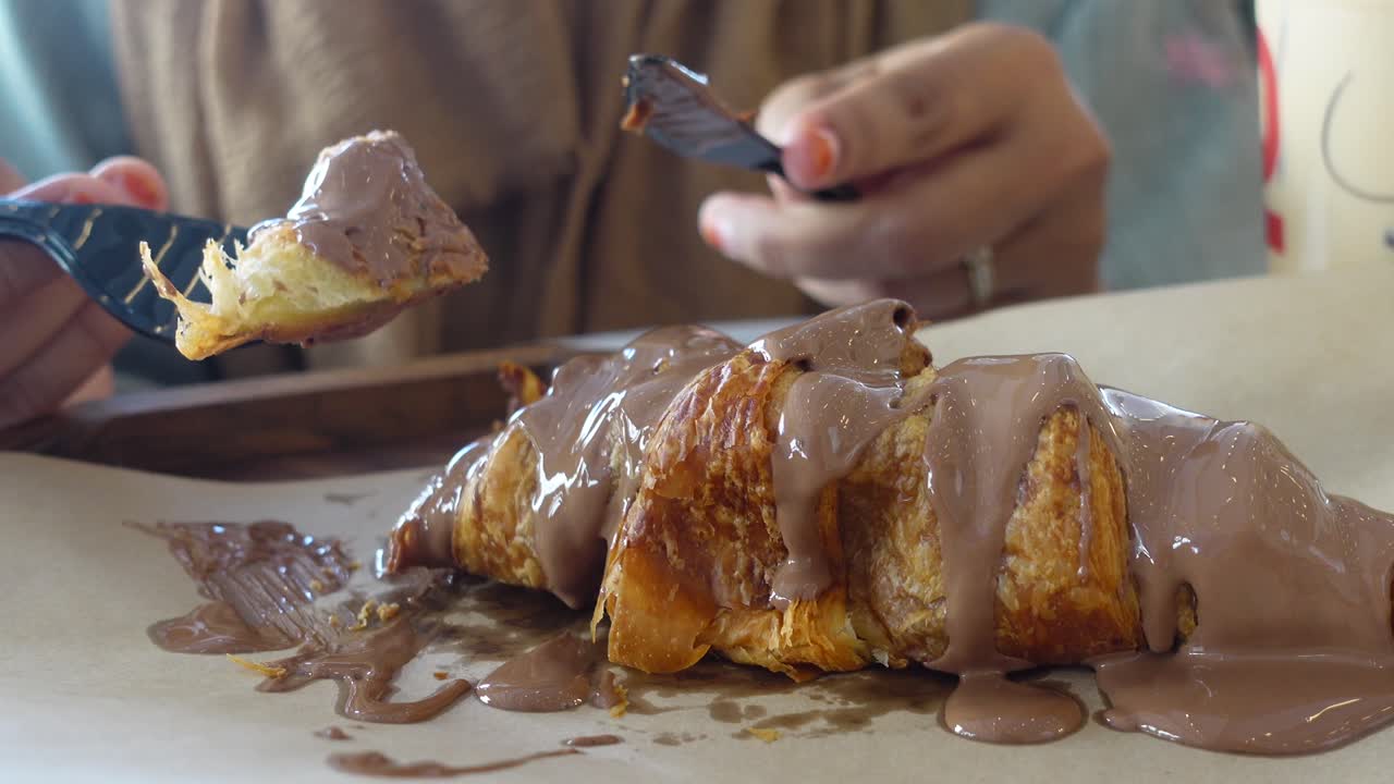 Donna che mangia un croissant al cioccolato.