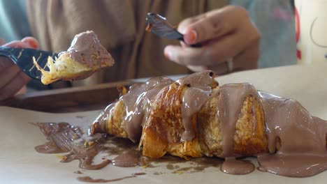 woman eating a chocolate croissant