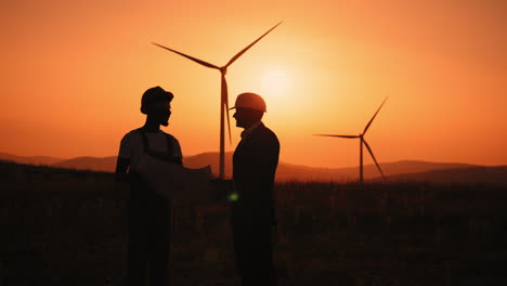 wind farm engineers discussing plans at sunset