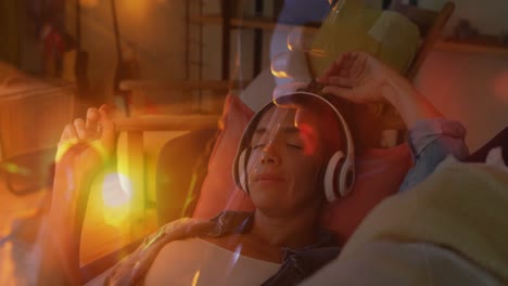 animación del paisaje del atardecer sobre una mujer biracial escuchando música con auriculares.