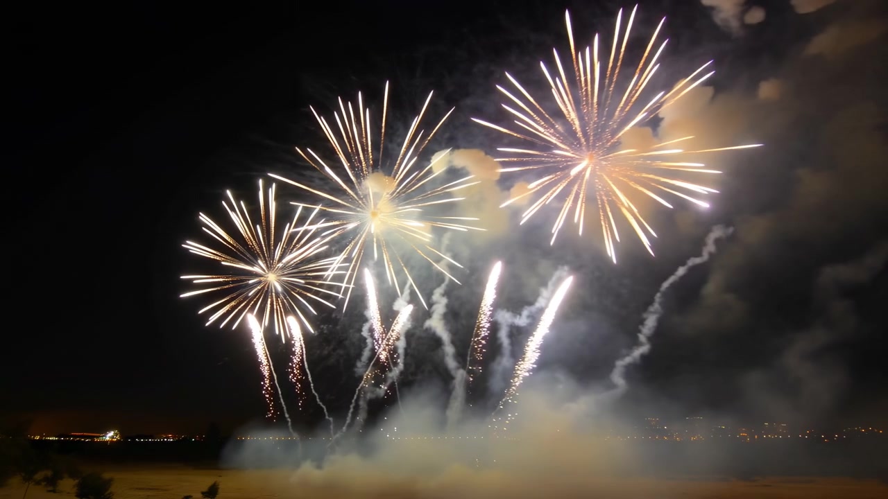 spectacular fireworks bursting and spreading across the night sky, creating a celebratory atmosphere with vibrant yellow and white colors, set against a clean background, offering ample cop.