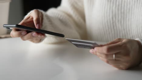 female hands holding credit card and using smartphone. online shopping