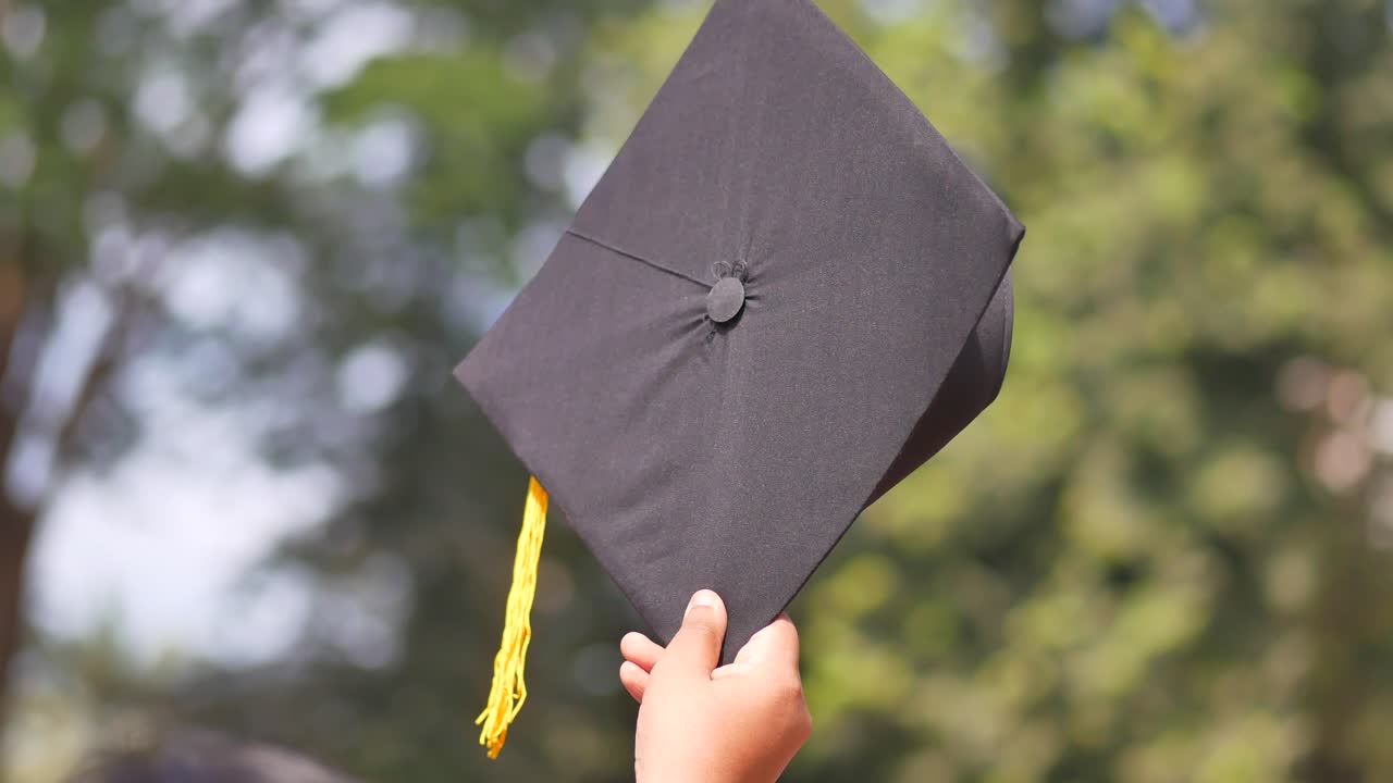 los estudiantes sostienen los sombreros en la mano durante el éxito de la graduación