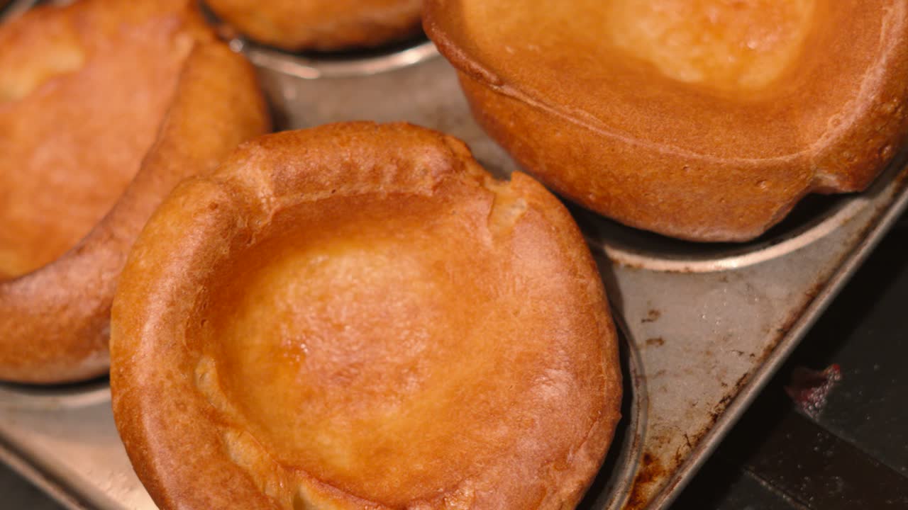 recién cocinado horneado británico tradicional yorkshire pudines en bandeja de metal después de salir del horno para añadir el domingo asado almuerzo cena 4k