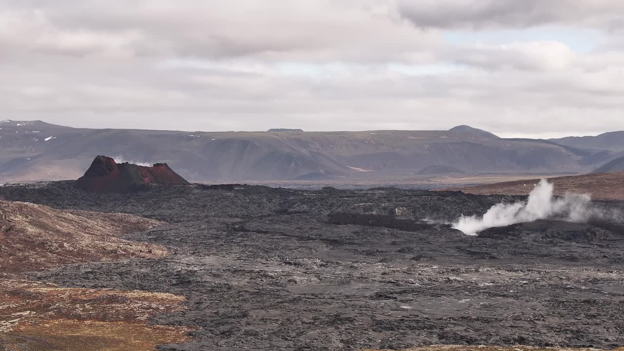 Vista de drone de uma cratera vulcânica na Islândia com campo de lava escura e fumarolas, terreno e paisagem acidentados