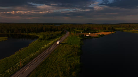 Vista-Aérea-Rodeando-Una-Casa-Rodante-Conduciendo-Por-La-Carretera-E75,-Tarde-De-Verano-En-Sodankyla,-Finlandia