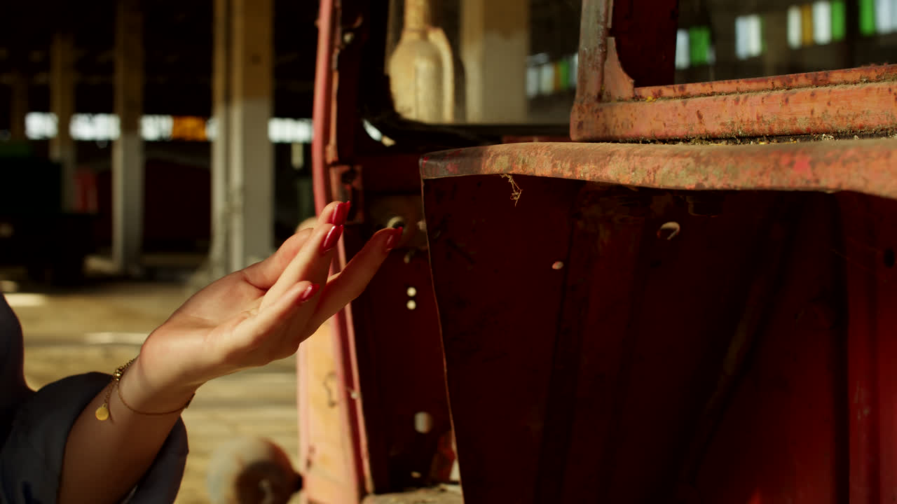 Woman's hand touching an old rusty car part in a factory