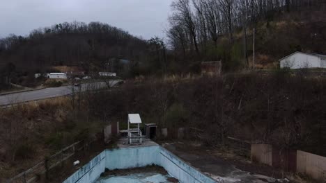 aerial drone footage pushing in over an overgrown wave pool in an abandoned water park